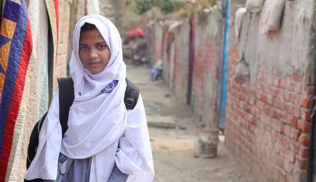 Child carrying a school bag on the way to school in a community setting