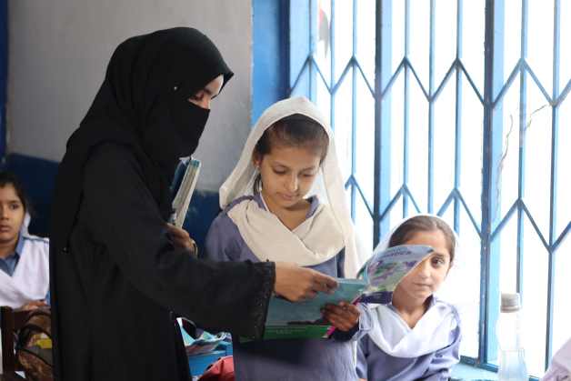 Teachers helping a girl understand a lesson in the classroom